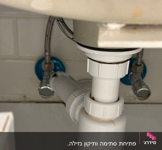 צנרת מתחת לכיור עם חיבורים וכלים